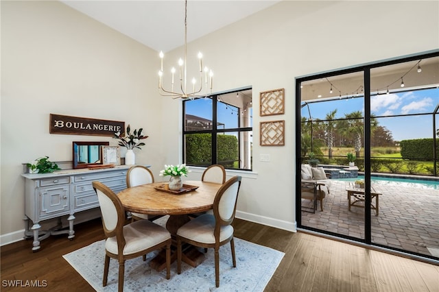 dining room featuring a chandelier, vaulted ceiling, baseboards, and dark wood-style floors