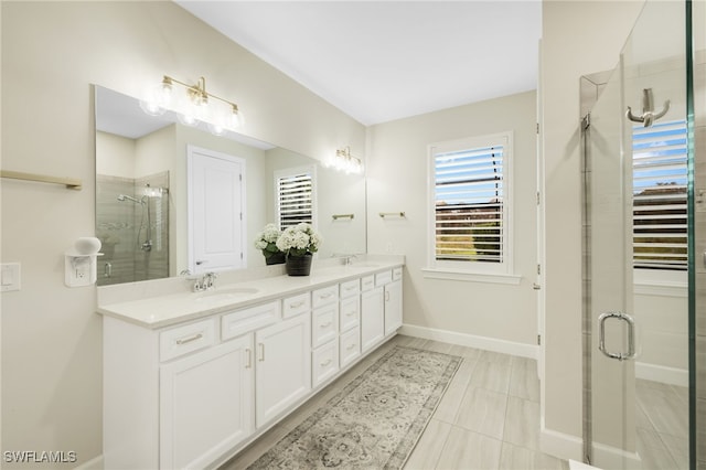 full bathroom featuring double vanity, a stall shower, a sink, and baseboards