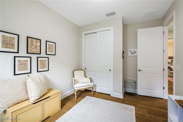 sitting room with wood finished floors, visible vents, and baseboards