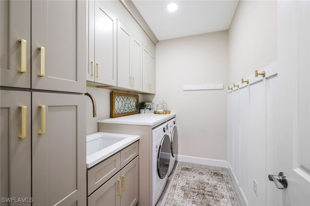 clothes washing area featuring cabinet space, baseboards, washer and clothes dryer, and a sink