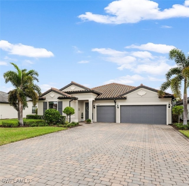 view of front facade with stucco siding, a tiled roof, decorative driveway, and an attached garage