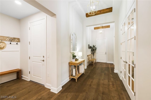 entrance foyer with a chandelier, dark wood-style flooring, and baseboards