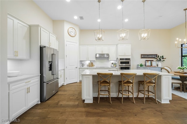 kitchen featuring visible vents, appliances with stainless steel finishes, dark wood-type flooring, light countertops, and under cabinet range hood