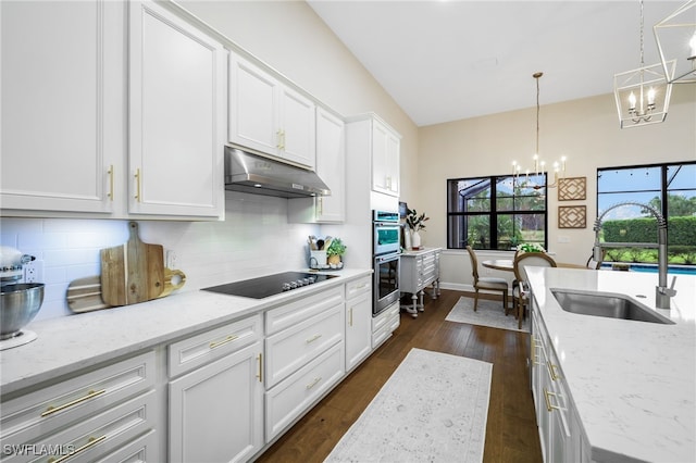 kitchen featuring tasteful backsplash, black electric stovetop, under cabinet range hood, a chandelier, and a sink