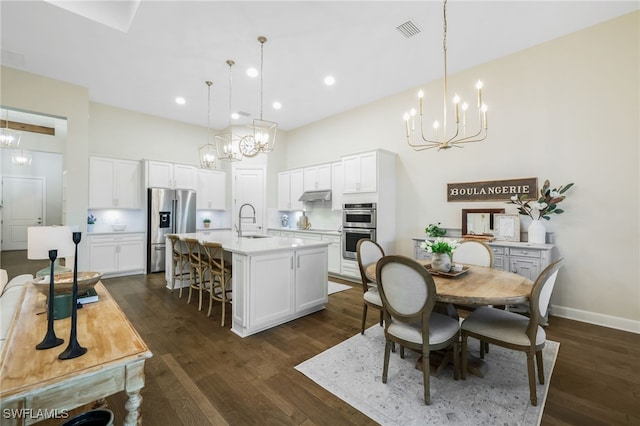 kitchen with visible vents, appliances with stainless steel finishes, dark wood-style flooring, an inviting chandelier, and under cabinet range hood