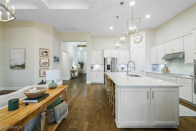 kitchen featuring white cabinets, under cabinet range hood, light countertops, and dark wood-type flooring