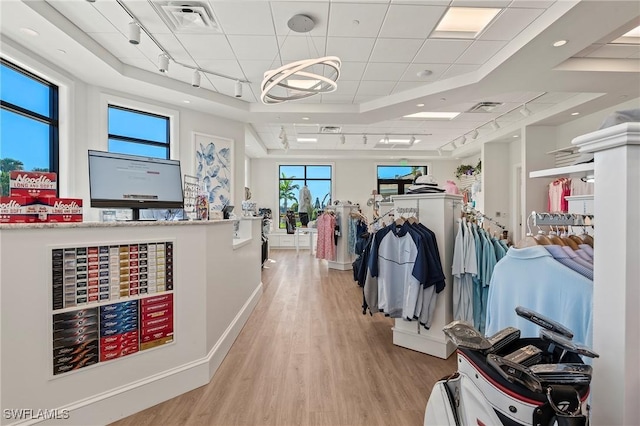 interior space with track lighting, a raised ceiling, visible vents, and light wood finished floors