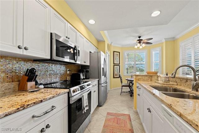 kitchen with appliances with stainless steel finishes, ornamental molding, a sink, white cabinetry, and backsplash