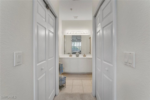 bathroom featuring tile patterned flooring, a closet, a textured wall, and double vanity