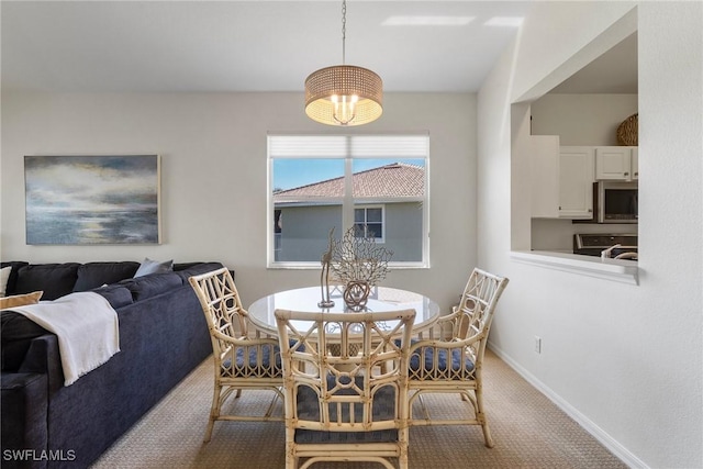 dining room with carpet, baseboards, and a notable chandelier