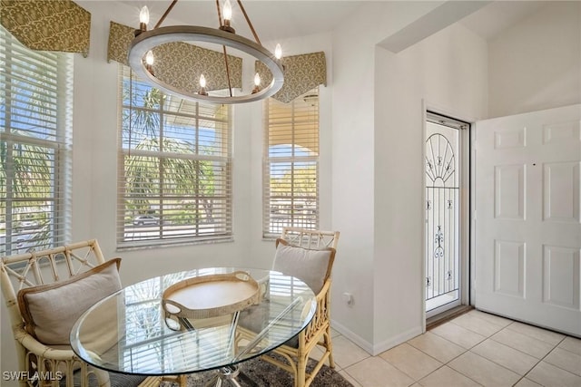 tiled dining area with a chandelier and baseboards