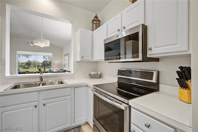 kitchen featuring stainless steel appliances, a sink, white cabinetry, light countertops, and pendant lighting