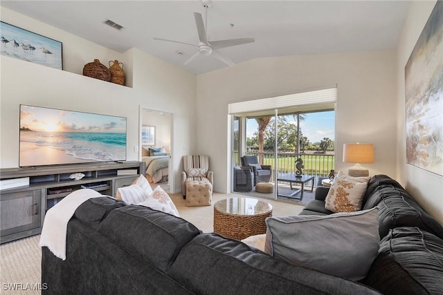 living area featuring light carpet, ceiling fan, visible vents, and vaulted ceiling