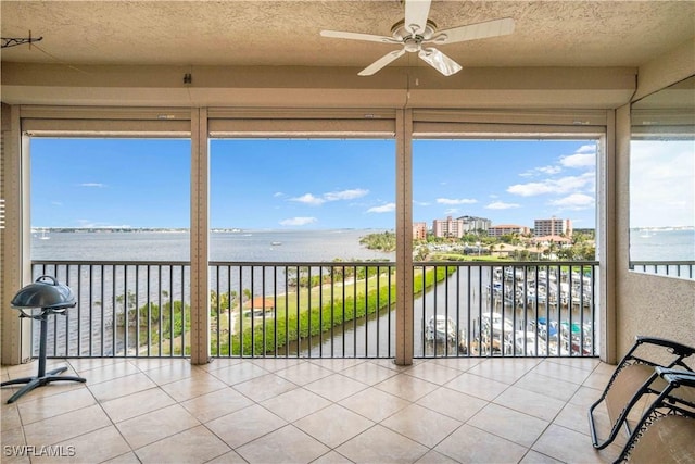 sunroom featuring a ceiling fan, a water view, and a city view