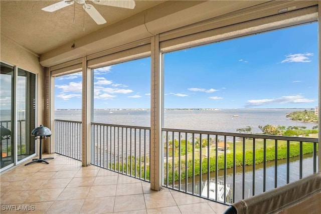 unfurnished sunroom featuring a water view and a ceiling fan