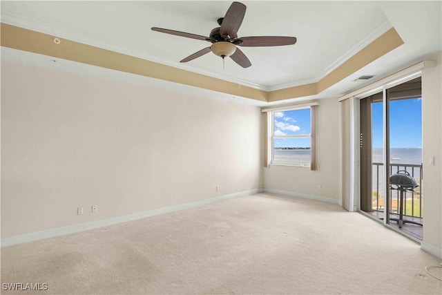 empty room featuring carpet floors, a tray ceiling, crown molding, and baseboards