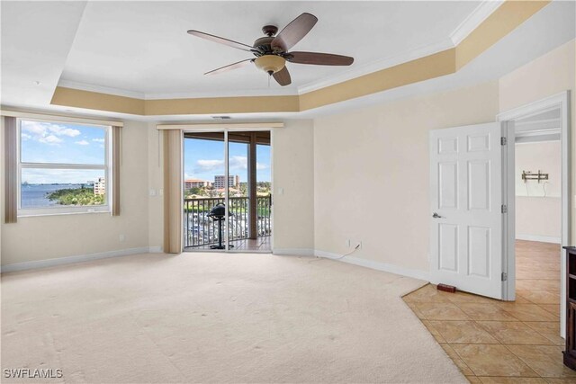 unfurnished room featuring ornamental molding, a tray ceiling, light carpet, and baseboards