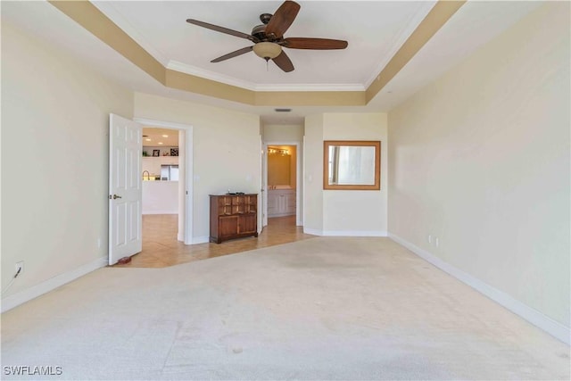 unfurnished bedroom featuring light carpet, baseboards, ornamental molding, and a raised ceiling