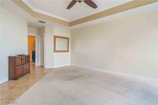 spare room with light carpet, baseboards, visible vents, ornamental molding, and a tray ceiling