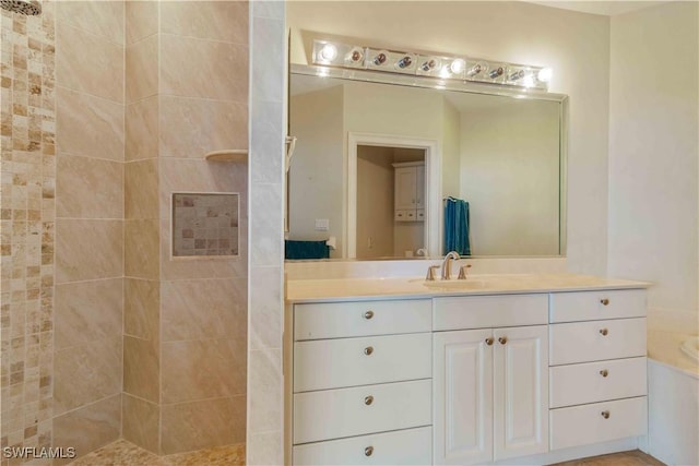 bathroom featuring tiled shower and vanity