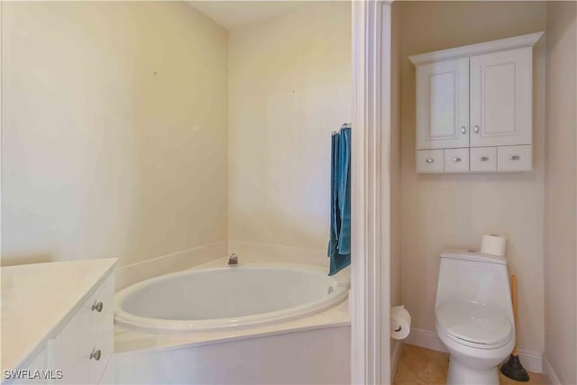 bathroom with a garden tub, toilet, vanity, baseboards, and tile patterned floors