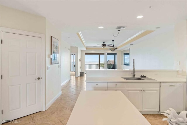 kitchen with white dishwasher, a sink, visible vents, light countertops, and a tray ceiling