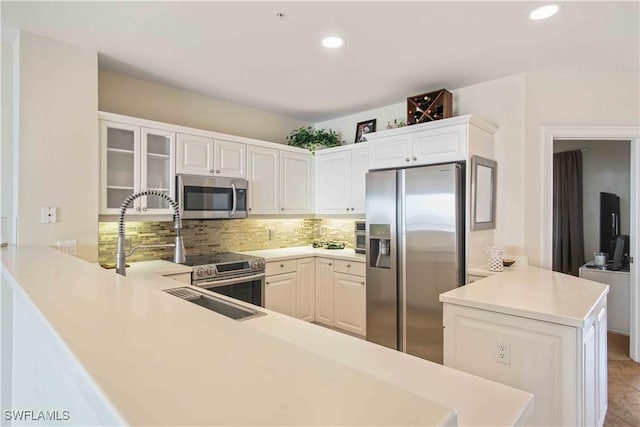 kitchen with recessed lighting, a peninsula, light countertops, appliances with stainless steel finishes, and tasteful backsplash