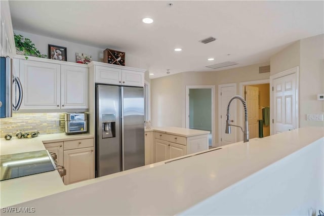 kitchen featuring recessed lighting, a peninsula, light countertops, appliances with stainless steel finishes, and backsplash