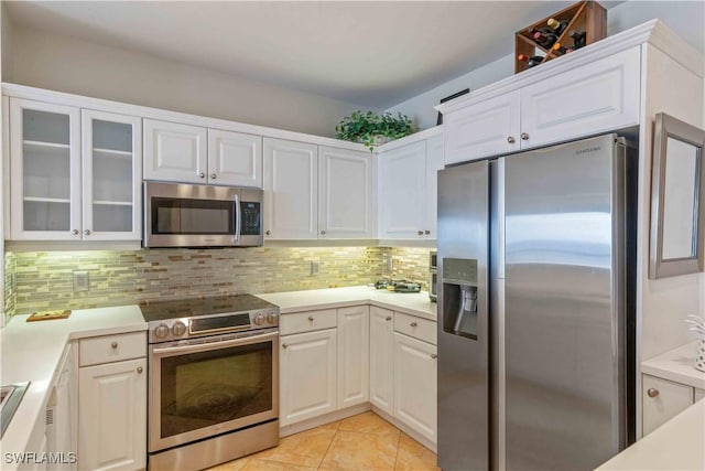 kitchen featuring light tile patterned floors, stainless steel appliances, white cabinetry, light countertops, and tasteful backsplash