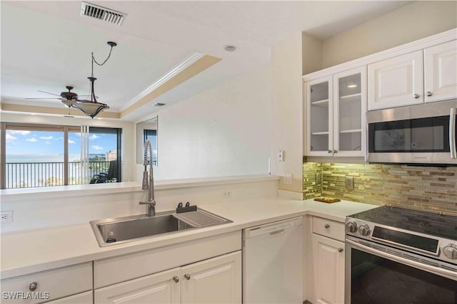 kitchen featuring visible vents, white cabinets, appliances with stainless steel finishes, a tray ceiling, and a sink