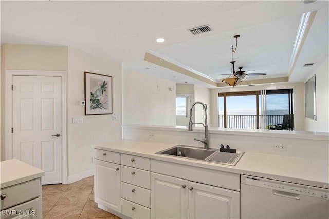 kitchen with a tray ceiling, light countertops, visible vents, a sink, and dishwasher