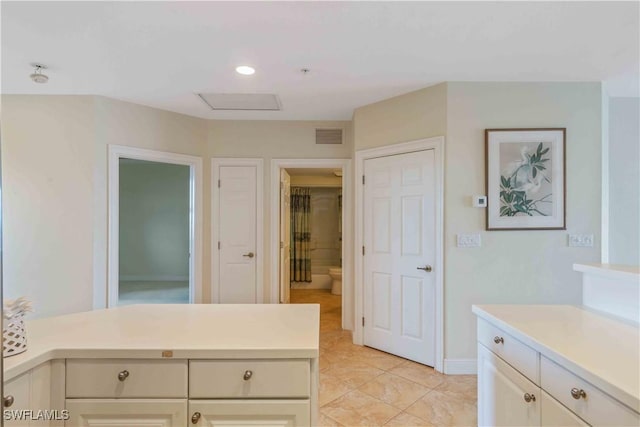 kitchen featuring light countertops, visible vents, a peninsula, and baseboards