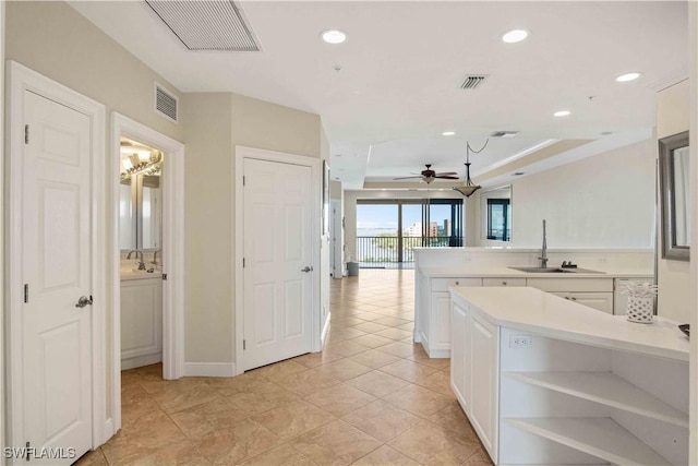 kitchen featuring white cabinetry, visible vents, a raised ceiling, and a sink