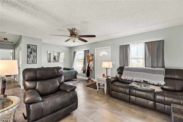 living area featuring a textured ceiling, baseboards, and a ceiling fan