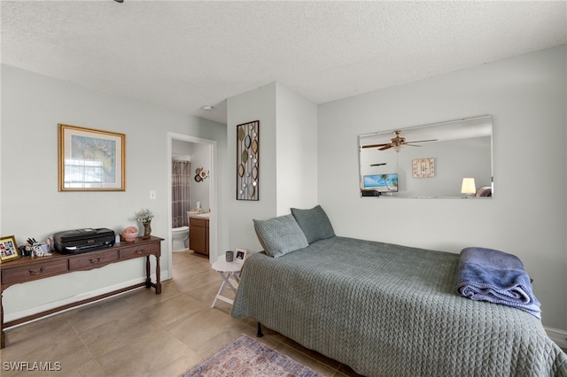 bedroom featuring a textured ceiling, ensuite bathroom, tile patterned flooring, and baseboards