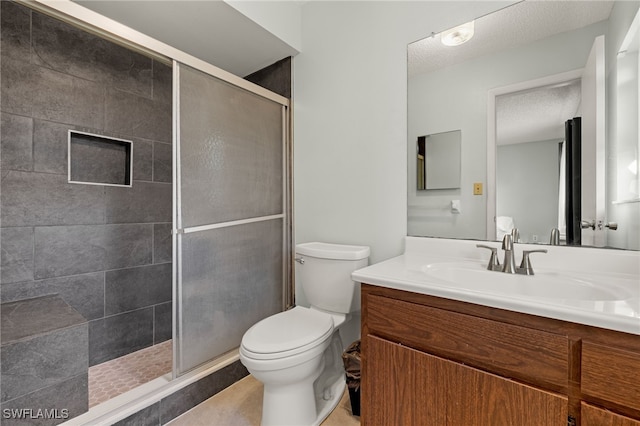 bathroom featuring a stall shower, a textured ceiling, toilet, and vanity