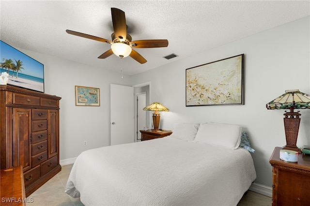 bedroom with a ceiling fan, visible vents, a textured ceiling, and baseboards