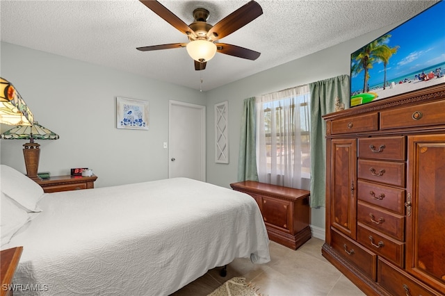 bedroom with a textured ceiling, light tile patterned floors, and a ceiling fan