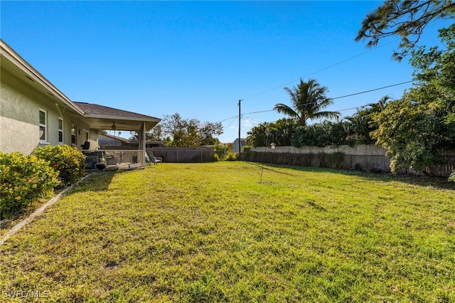 view of yard with a fenced backyard and ceiling fan