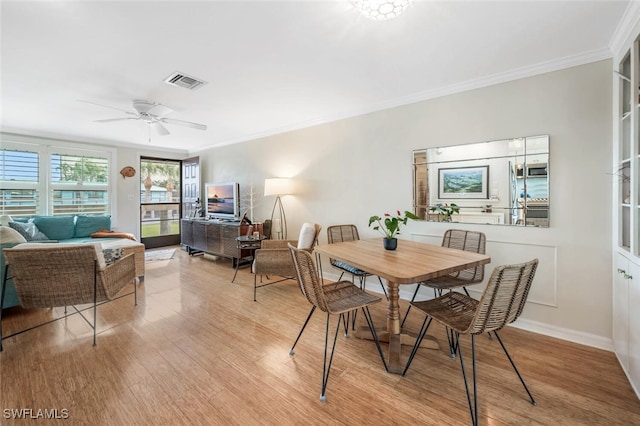 dining room featuring crown molding, visible vents, a ceiling fan, wood finished floors, and baseboards