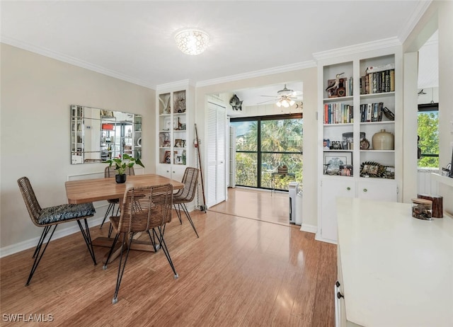 dining space with light wood-style flooring, built in features, a wealth of natural light, and crown molding