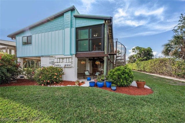 view of front of home with stairs, board and batten siding, and a front yard