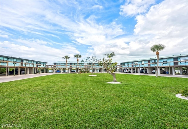 view of community with covered parking and a lawn