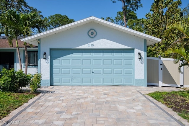 garage with decorative driveway and a gate