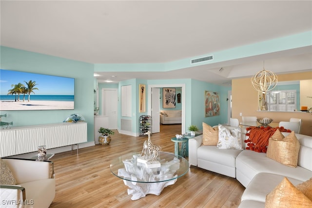 living room featuring visible vents, a notable chandelier, and wood finished floors