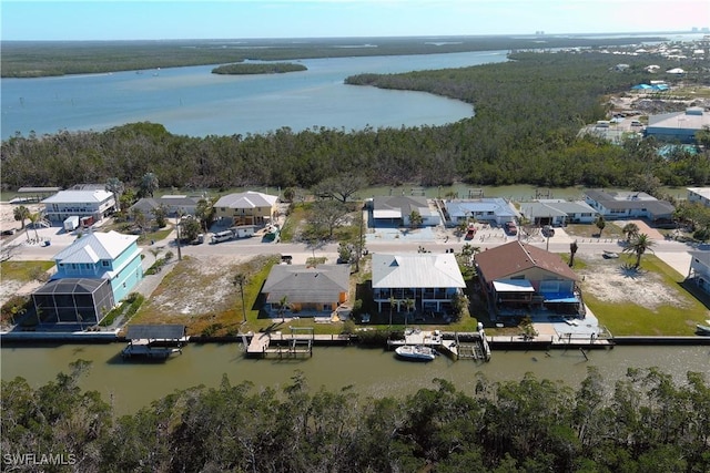 drone / aerial view featuring a water view, a wooded view, and a residential view