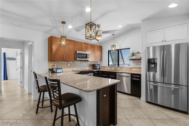 kitchen with light tile patterned floors, stainless steel appliances, a peninsula, and a sink