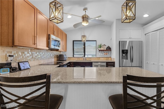 kitchen featuring stainless steel appliances, a peninsula, a kitchen breakfast bar, vaulted ceiling, and backsplash