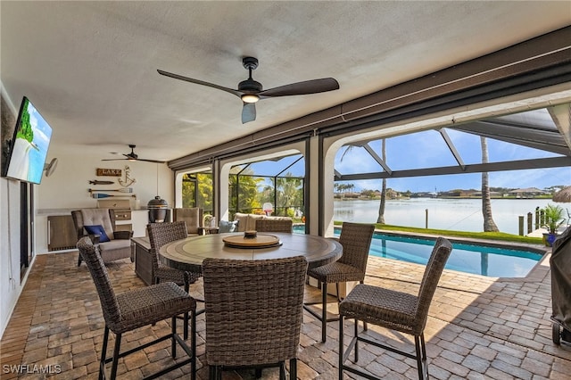 sunroom featuring ceiling fan and a water view