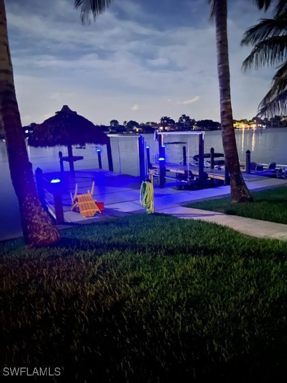 view of dock with a water view and a lawn